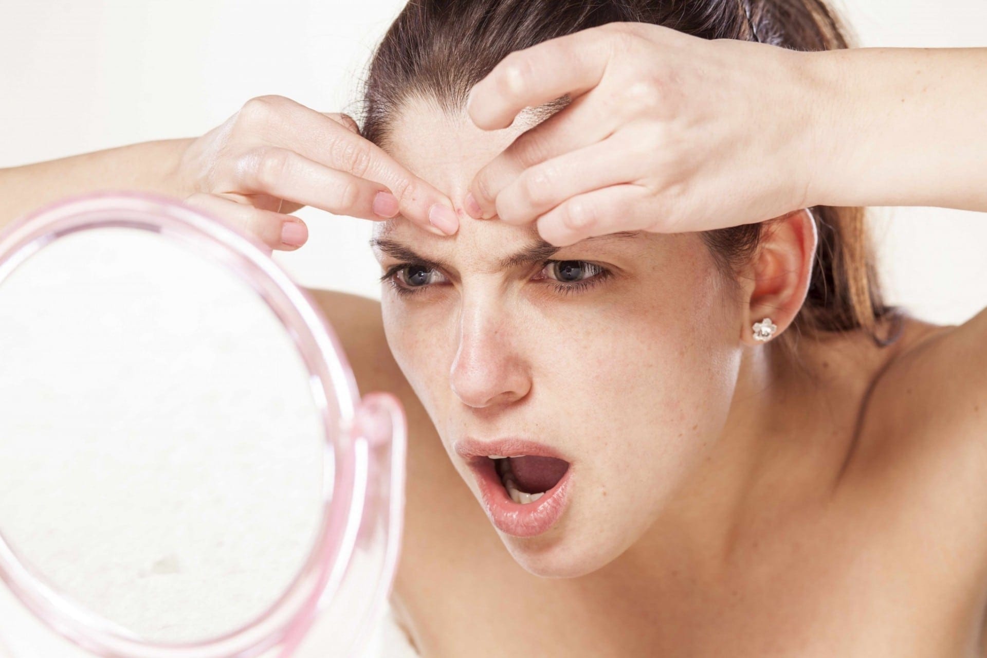 Young Woman Squeeze Her Acne In Front Of The Mirror